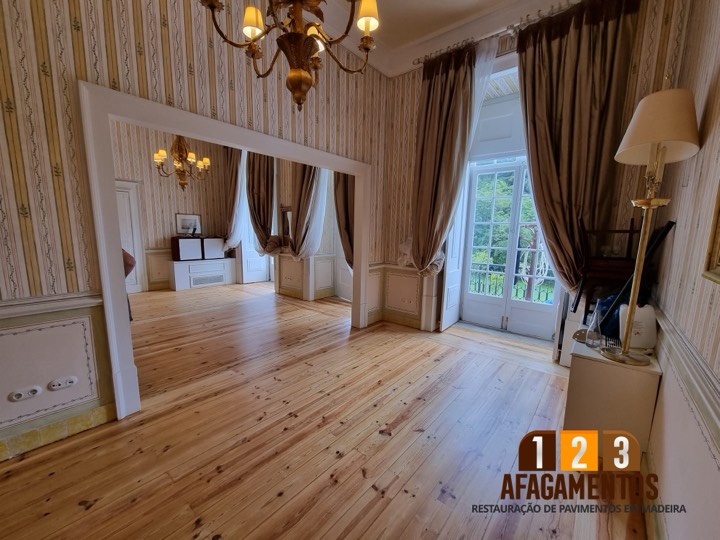Depois: sala com cortinados, com o soalho envernizado