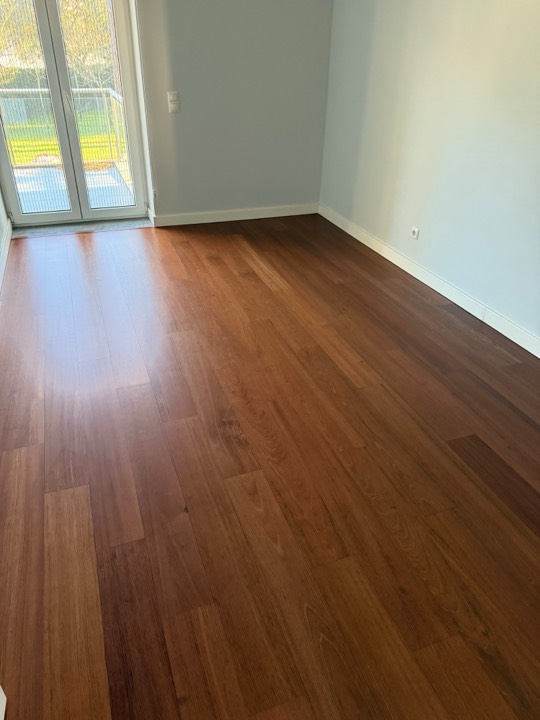 Soalho de madeira castanha envernizado, junto a uma porta para o jardim