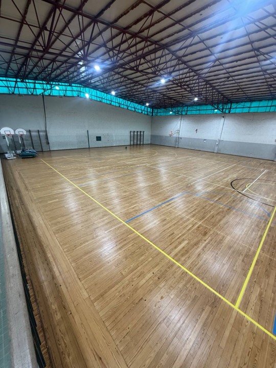 Pavimento de madeira de um pavilhão desportivo, com as marcações dos campos, renovado e envernizado