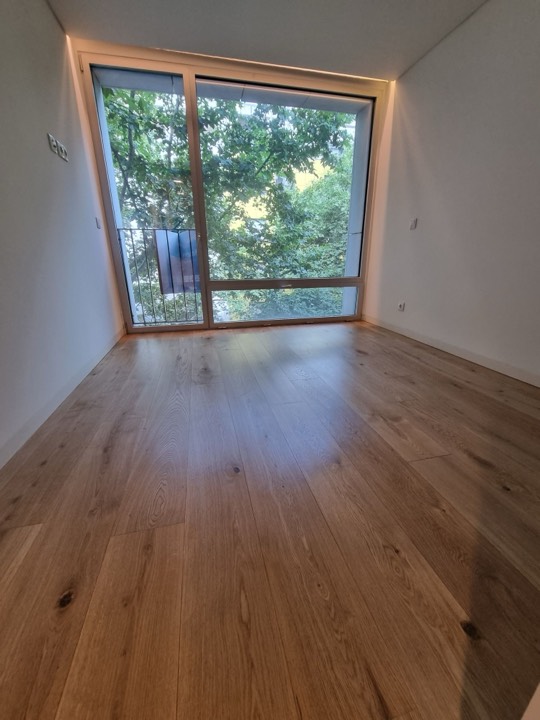 Soalho de carvalho de tábua larga num quarto com janela para as árvores